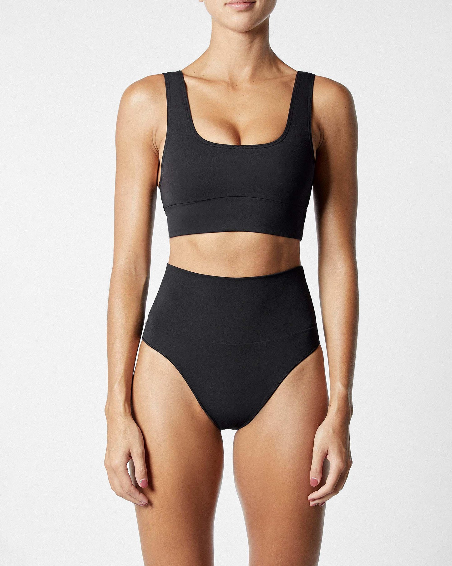 Studio image of model wearing the Contour High Waist Pant in Black, showcasing its high-rise compression fit. 