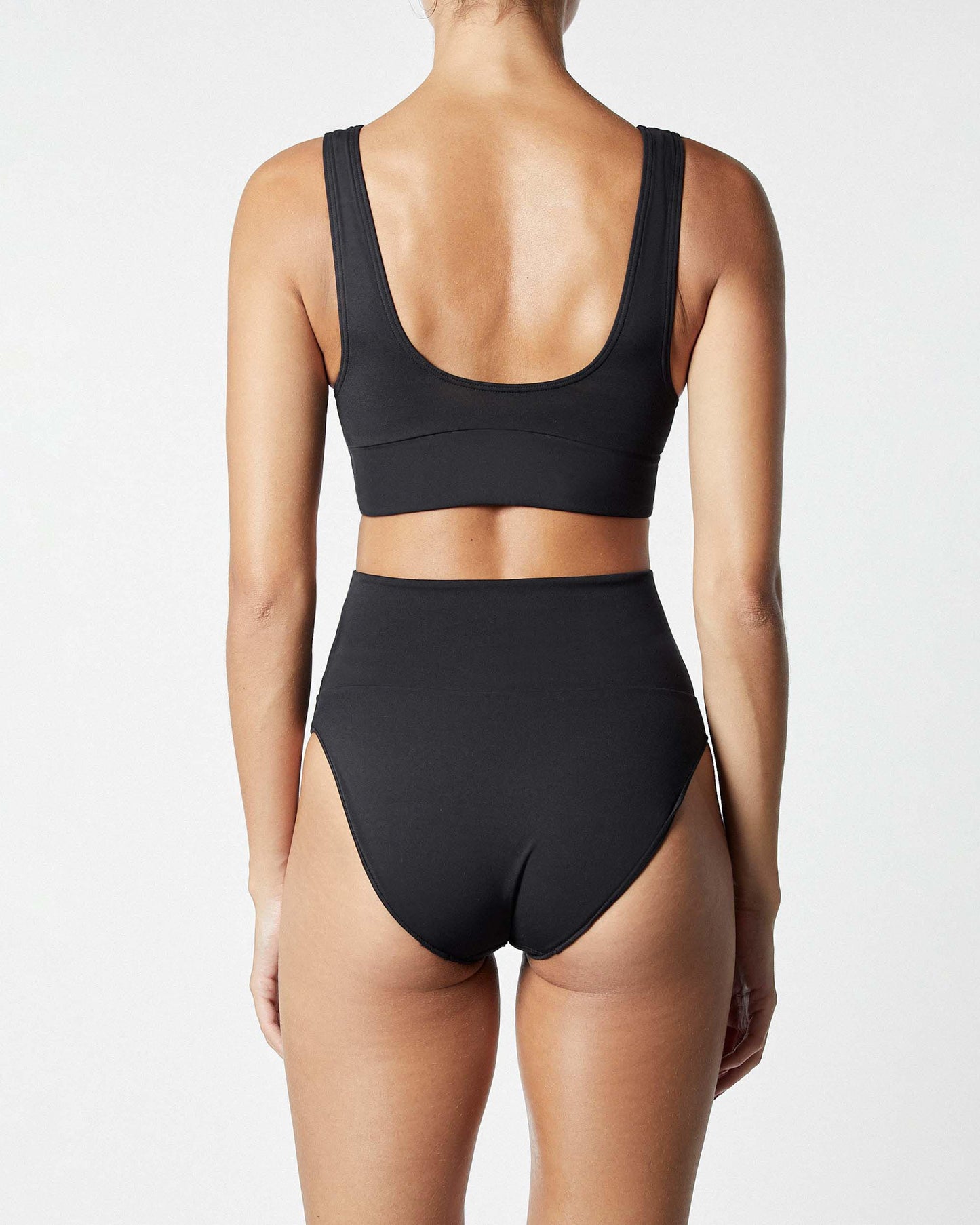 Studio image of model wearing the Contour High Waist Pant in Black, showcasing its moderate bottom coverage. 